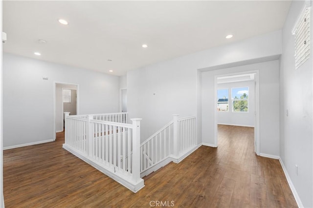 hallway with baseboards, hardwood / wood-style flooring, an upstairs landing, and recessed lighting