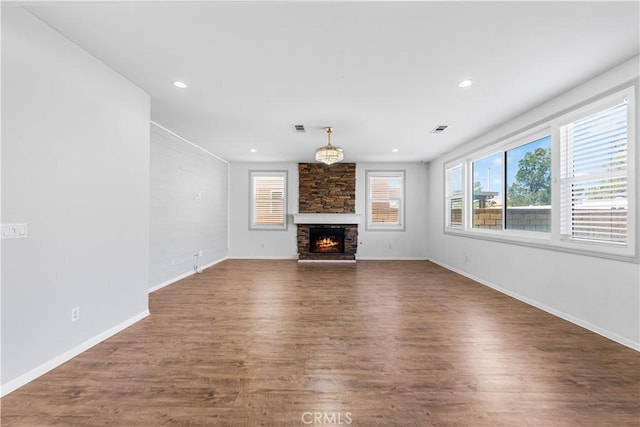 unfurnished living room with visible vents, a fireplace, baseboards, and wood finished floors