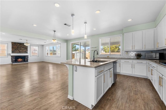 kitchen with a fireplace, tasteful backsplash, visible vents, stainless steel microwave, and a sink