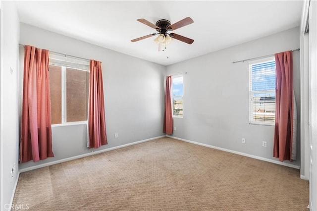 carpeted empty room featuring a ceiling fan and baseboards