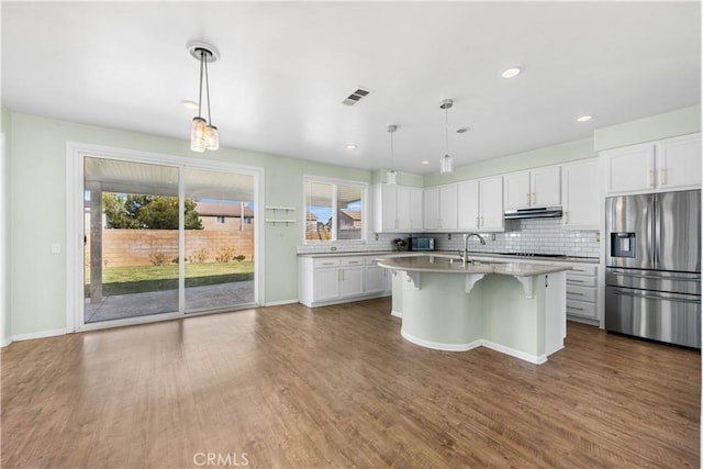 kitchen with visible vents, decorative backsplash, stainless steel fridge with ice dispenser, light countertops, and under cabinet range hood