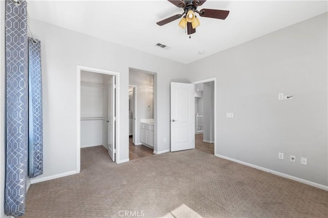 unfurnished bedroom with ceiling fan, baseboards, a spacious closet, a closet, and carpet