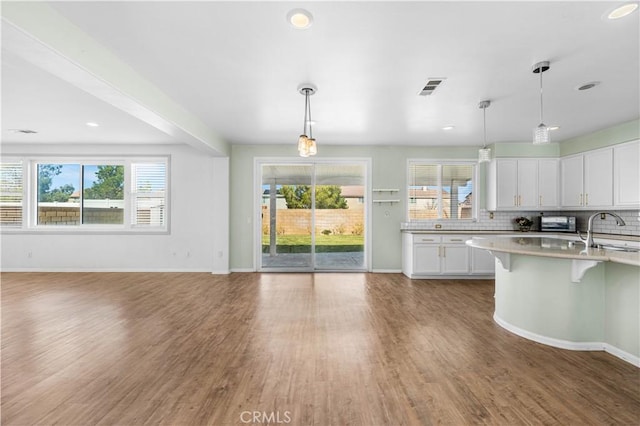 kitchen featuring tasteful backsplash, visible vents, a sink, and wood finished floors