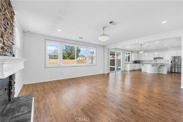 unfurnished living room with wood finished floors, a glass covered fireplace, visible vents, and recessed lighting