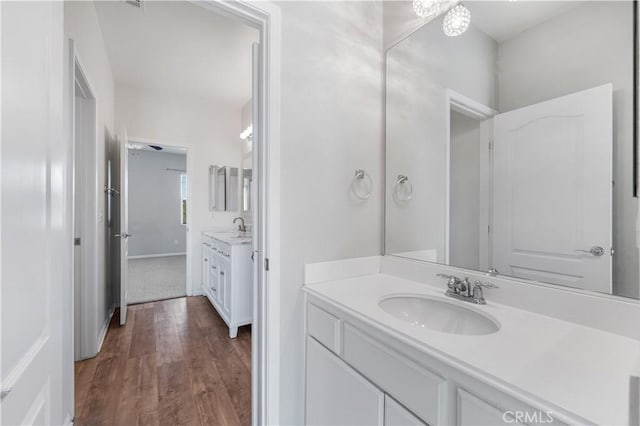 bathroom with two vanities, a sink, and wood finished floors