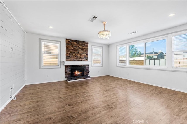 unfurnished living room with a fireplace, wood finished floors, visible vents, and baseboards