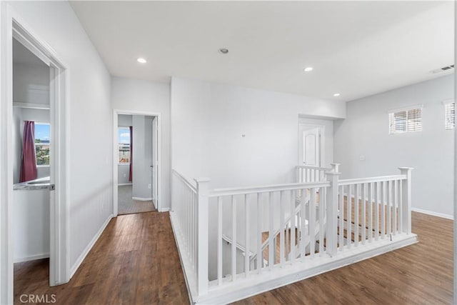 corridor featuring visible vents, plenty of natural light, wood finished floors, and an upstairs landing