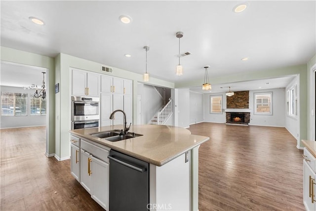 kitchen with visible vents, dishwashing machine, open floor plan, a fireplace, and a sink