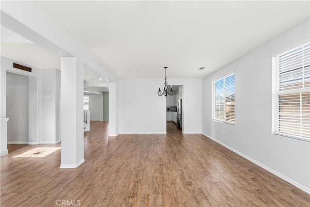 interior space with visible vents, a notable chandelier, baseboards, and wood finished floors