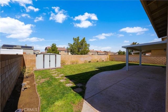 view of yard with an outbuilding, a storage unit, a patio area, and a fenced backyard