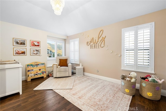 interior space with dark wood-style flooring, an inviting chandelier, and baseboards