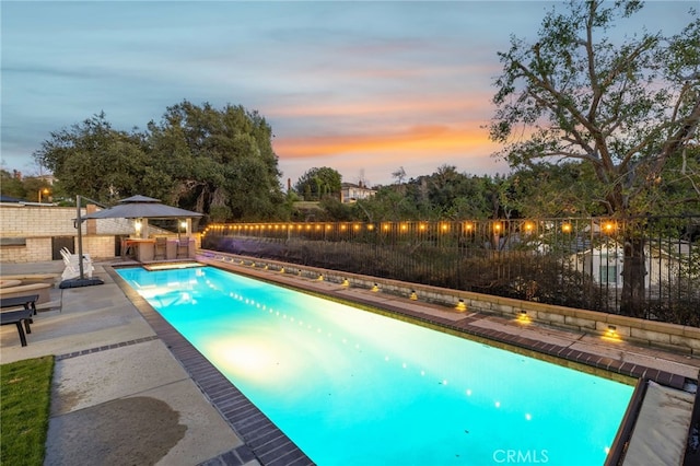 pool at dusk featuring a fenced in pool, a fenced backyard, a patio, and a gazebo