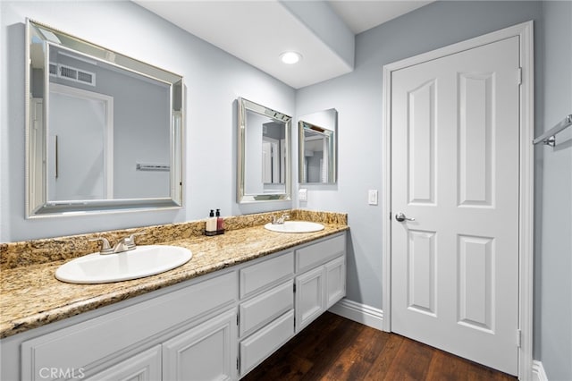 bathroom with double vanity, wood finished floors, a sink, and visible vents