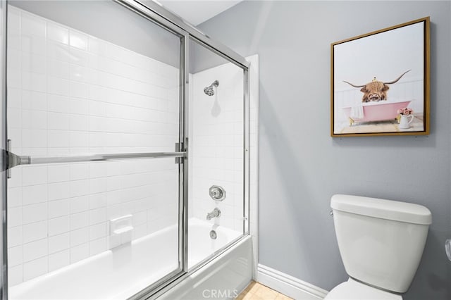 full bathroom with enclosed tub / shower combo, toilet, and baseboards