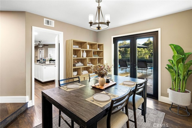 dining area featuring a chandelier, dark wood-type flooring, visible vents, baseboards, and french doors