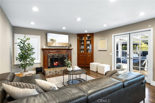 living area featuring french doors, a stone fireplace, dark wood-style flooring, and recessed lighting