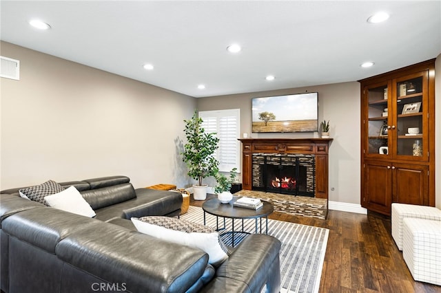 living room with dark wood-style flooring, a fireplace, recessed lighting, visible vents, and baseboards