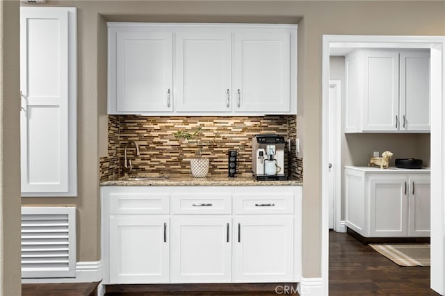 bar featuring dark wood-style floors, backsplash, a sink, and visible vents