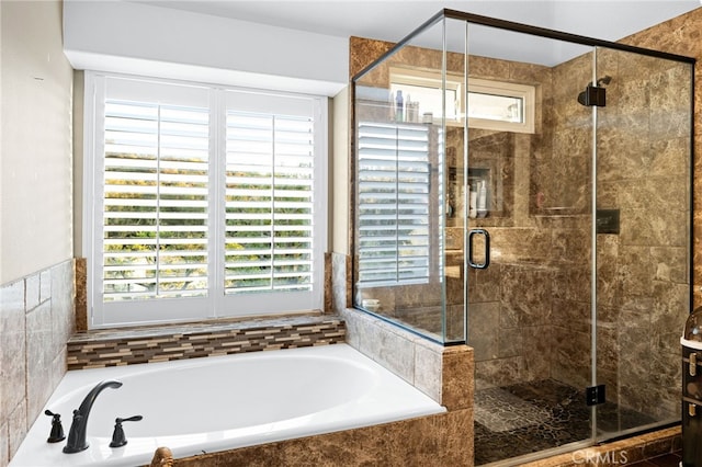 bathroom featuring a stall shower, a bath, and a healthy amount of sunlight