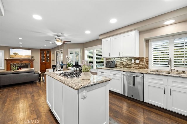 kitchen featuring a stone fireplace, appliances with stainless steel finishes, dark wood-style flooring, and a sink