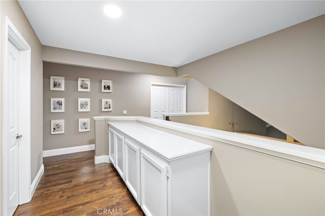 corridor with dark wood-style floors and baseboards