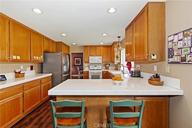 kitchen with a peninsula, white appliances, a sink, and light countertops