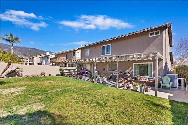 rear view of property with a yard, stucco siding, a pergola, and a patio