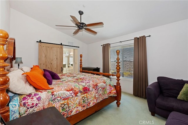 carpeted bedroom with a ceiling fan, vaulted ceiling, ensuite bathroom, and a barn door