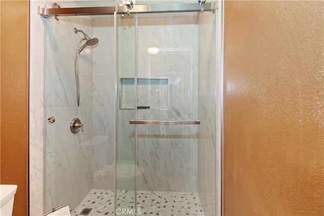 full bath featuring a marble finish shower and toilet