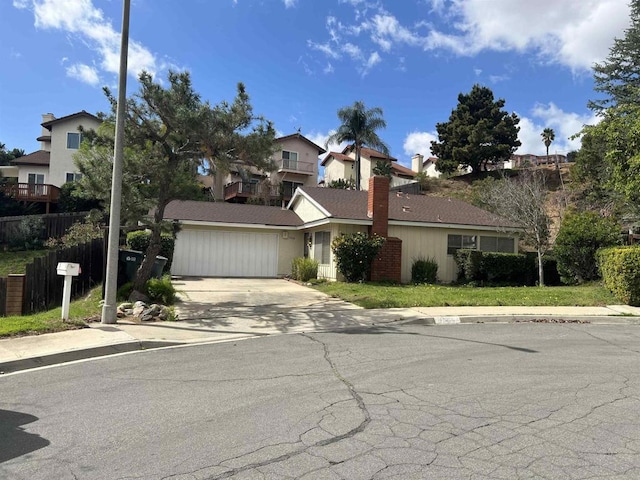 view of front of home featuring driveway, a garage, a chimney, a residential view, and fence