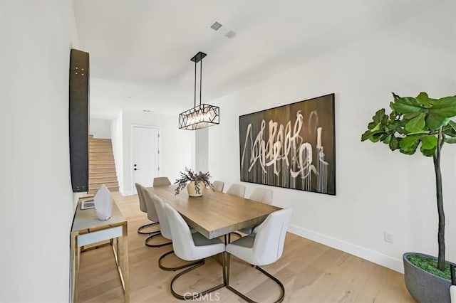 dining space featuring light wood-style floors, visible vents, and baseboards