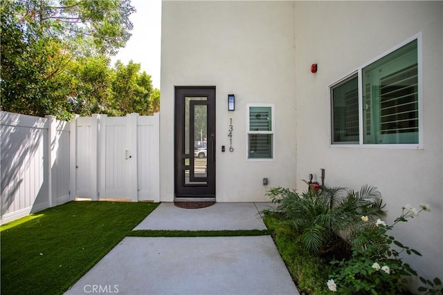 property entrance featuring fence and stucco siding