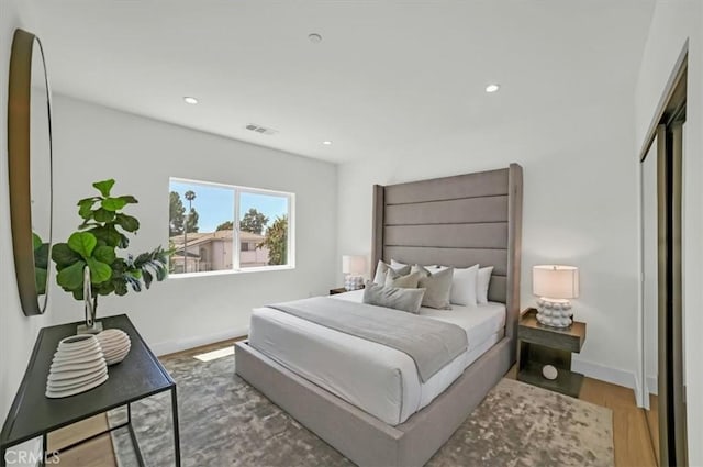 bedroom with recessed lighting, wood finished floors, visible vents, and baseboards