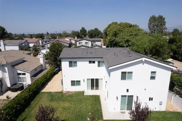 back of house with a yard, fence, a residential view, and stucco siding