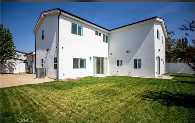 rear view of house featuring stucco siding, fence, a patio, and a yard