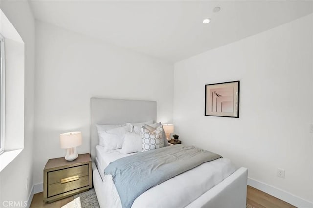 bedroom with recessed lighting, wood finished floors, and baseboards