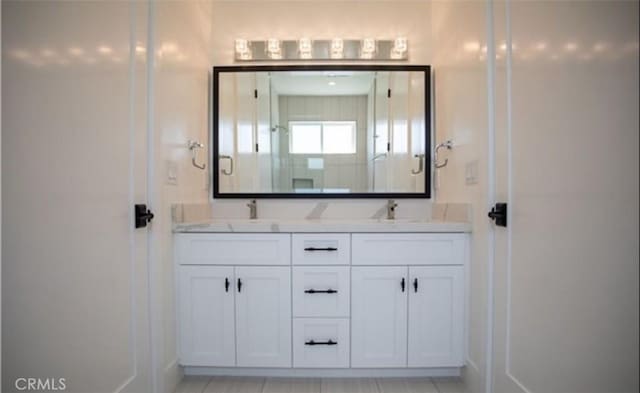 full bath featuring a shower with door, a sink, and double vanity