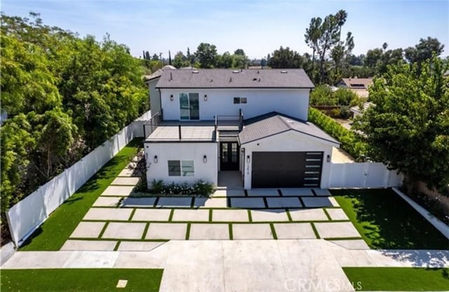 back of property with a yard, stucco siding, a garage, a fenced backyard, and driveway