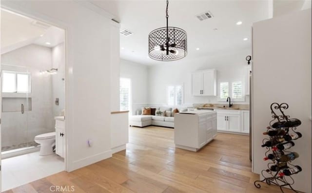 kitchen featuring light wood-style floors, visible vents, white cabinets, and a sink