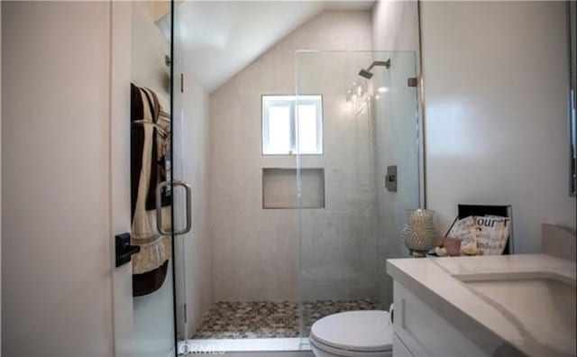 bathroom with toilet, a stall shower, vanity, and lofted ceiling