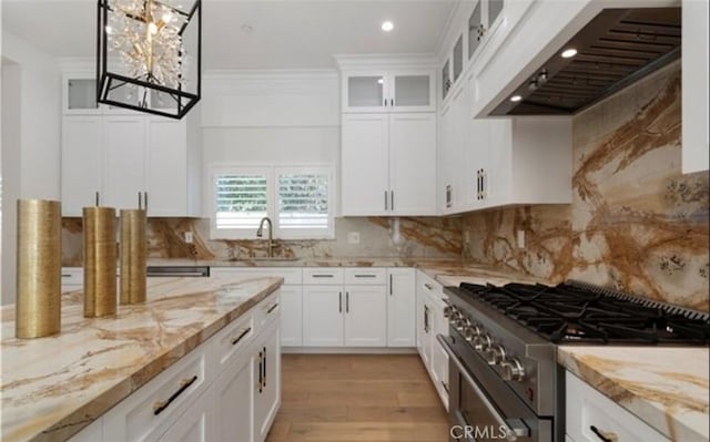 kitchen featuring high end stove, range hood, ornamental molding, and light stone counters