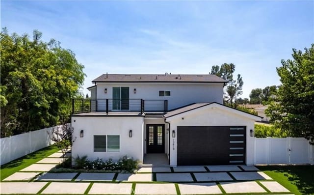 exterior space with an attached garage, stucco siding, fence, and french doors