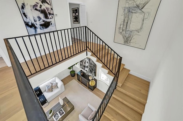 stairway featuring a high ceiling, wood finished floors, and baseboards