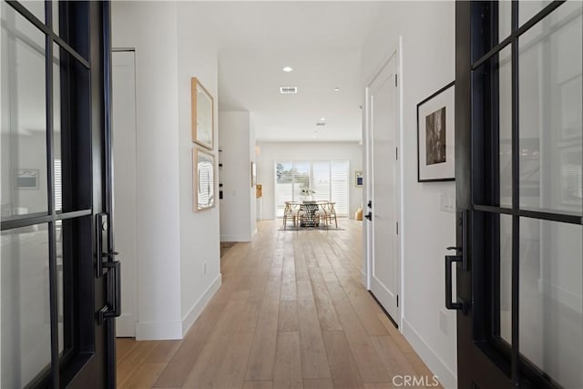 corridor with visible vents, baseboards, recessed lighting, and light wood-style floors