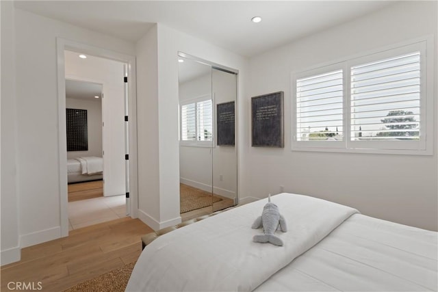 bedroom with recessed lighting, a closet, baseboards, and wood finished floors