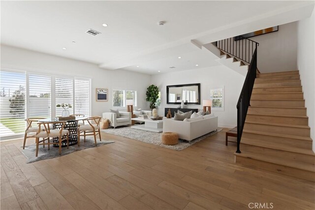 living area featuring visible vents, stairway, wood-type flooring, and recessed lighting