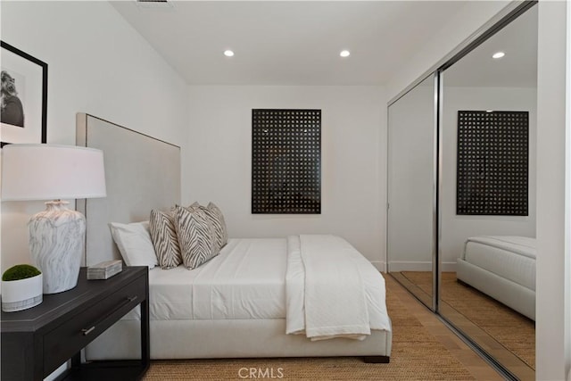 bedroom with wood finished floors, a closet, and recessed lighting