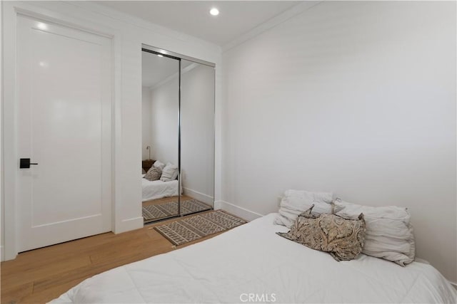 bedroom with crown molding, a closet, recessed lighting, and wood finished floors