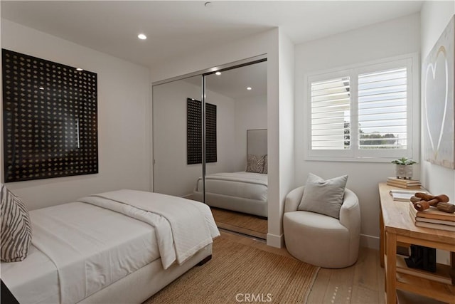bedroom featuring wood finished floors, a closet, baseboards, and recessed lighting