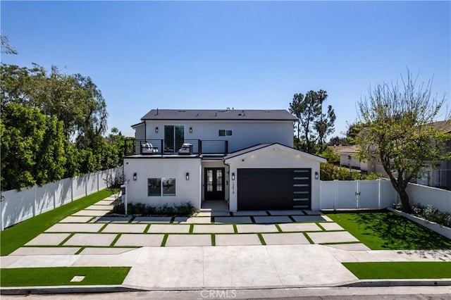 back of house featuring a balcony, fence private yard, stucco siding, an attached garage, and a gate